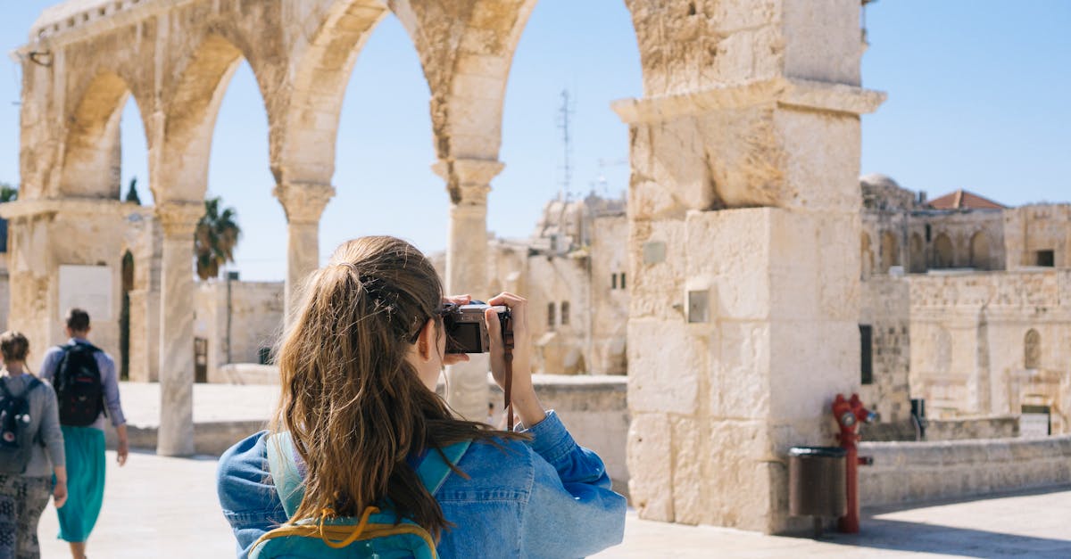 A tourist photographs the ancient stone arches in Jerusalem's Old Town, capturing the essence of travel and history.