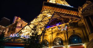 Night view of the Eiffel Tower replica at Paris Las Vegas, showcasing vibrant lights and architecture.