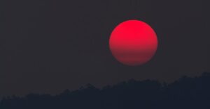 A captivating blood moon rising over a silhouette of hills, capturing the beauty of twilight.