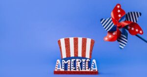 A vibrant blue background with a patriotic decoration featuring a glittery Uncle Sam hat and a red, white, and blue pinwheel.