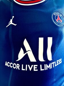 Detailed view of Paris Saint-Germain jersey with sponsor logos and design elements.